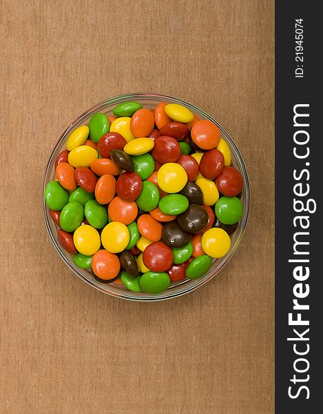 Colorful chocolate candy in the glass bowl with wooden background