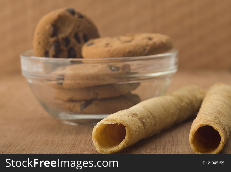 Egg rolls and chocolate chip biscuits shot on wooden background. Egg rolls and chocolate chip biscuits shot on wooden background