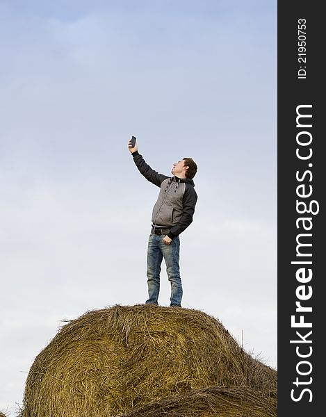 Man catch mobile signal standing at haystack