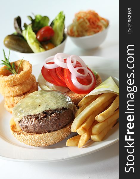 Western beef burger served with onion rings and fries as side dishes