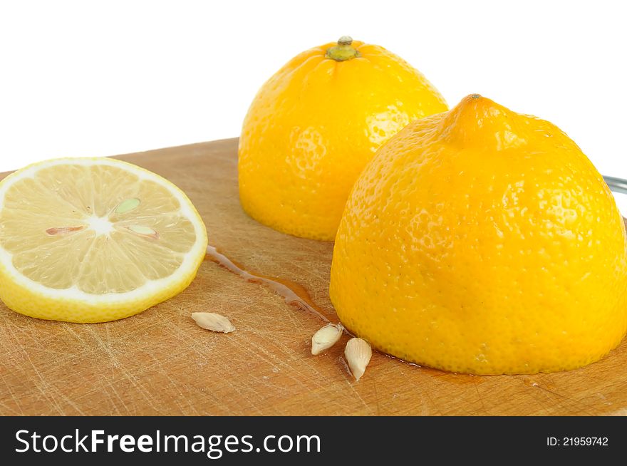 A cut lemon with seeds on a wooden cutting board against a white background. A cut lemon with seeds on a wooden cutting board against a white background