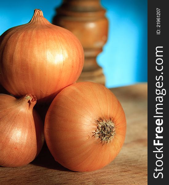 A group of onions on brown wooden desk with blue background