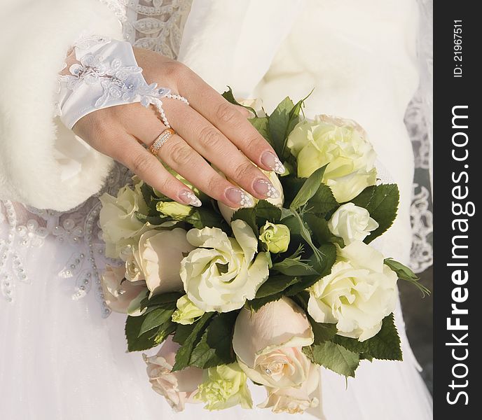 Hand of fiancee with a wedding ring lies on a bouquet from roses. Hand of fiancee with a wedding ring lies on a bouquet from roses