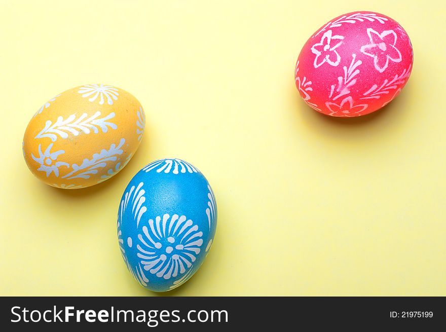 Handmade Easter eggs on a yellow background.