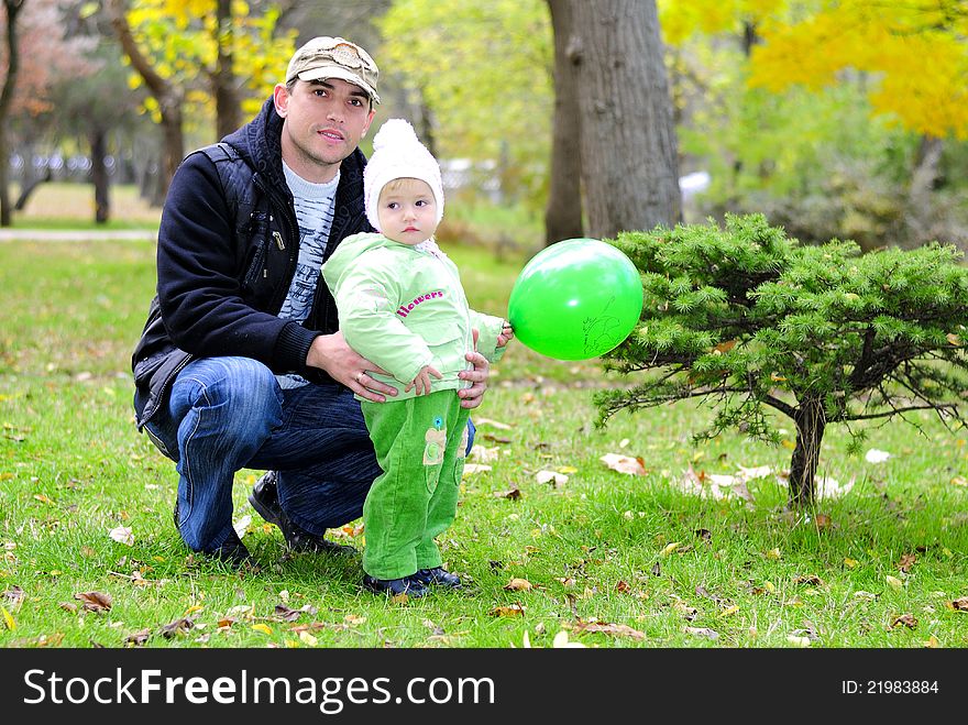 Small beautiful girl in green suit with father on green glade and with green air ball. Small beautiful girl in green suit with father on green glade and with green air ball