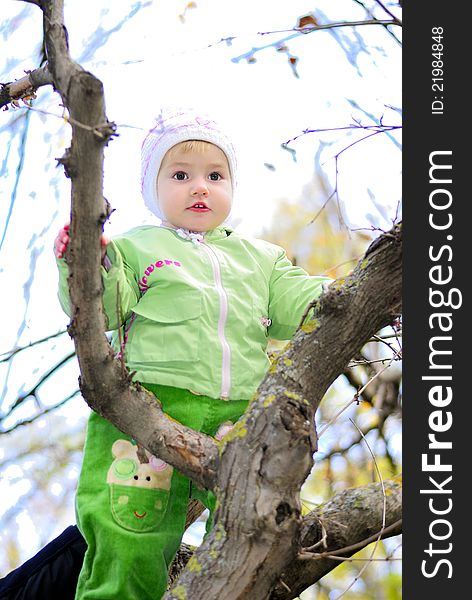Small girl on tree by autumn In wood