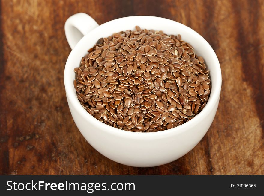 Linseeds In Cup On Wooden Background