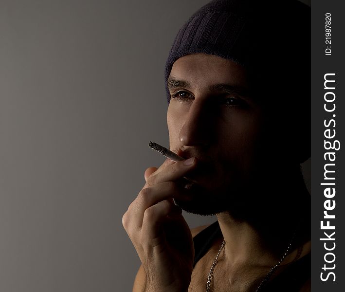 Portrait of a young man with a cigarette in the dark
