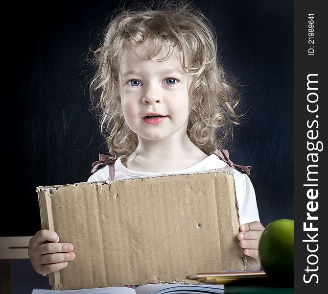 Schoolchild with paper blank in class against blackboard. School concept