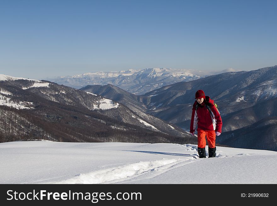 Happy woman climbing mountains in winter with beautiful lanscape behind