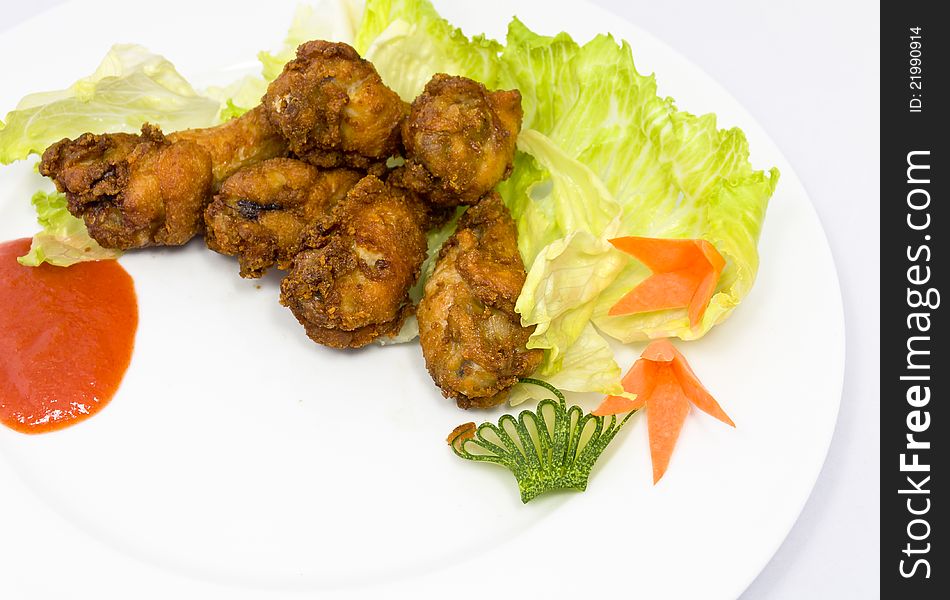 Fried chicken wings with vegetables at the background.