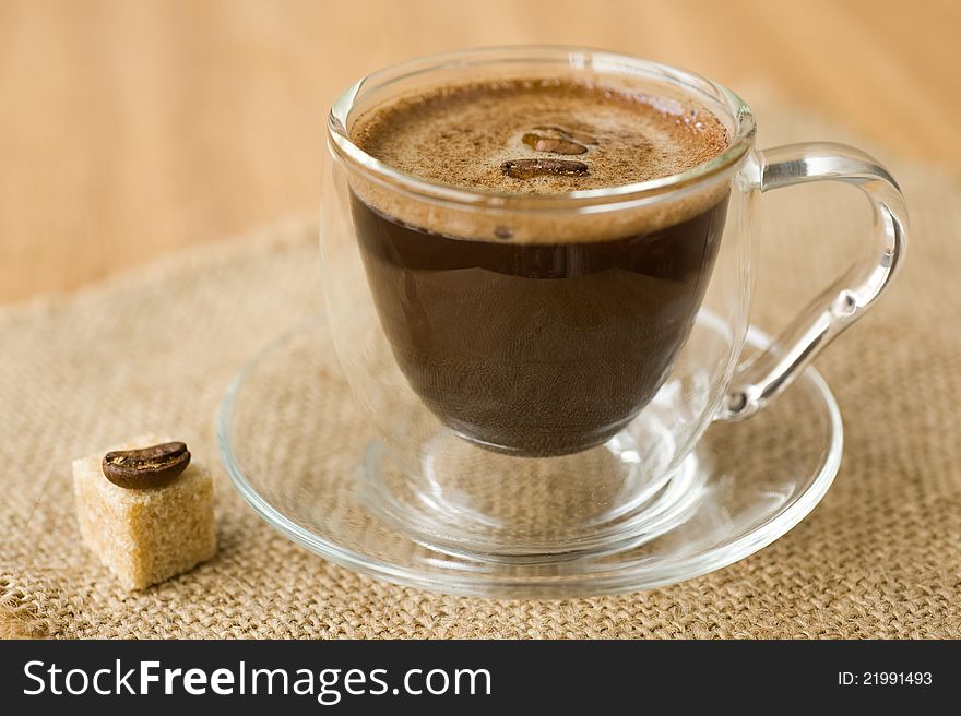 Cup of coffee, sugar, coffee beans on a napkin of burlap