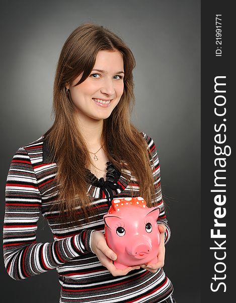 Woman with a piggybank isolated on  grey  background