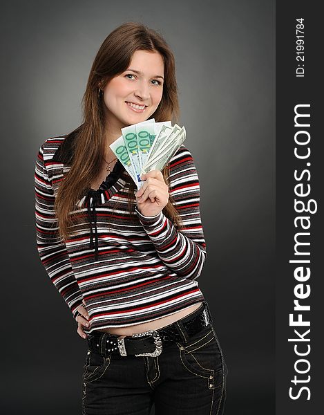 Pretty woman smiling while holding fan made of money  on a  grey background. Pretty woman smiling while holding fan made of money  on a  grey background