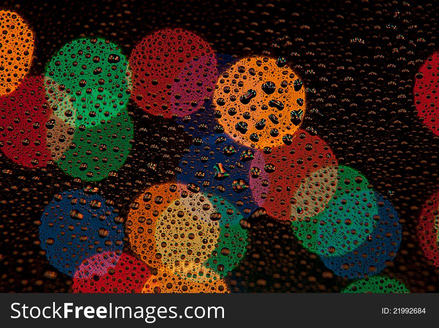 Color Bokeh on dark background with drops in the foreground. Color Bokeh on dark background with drops in the foreground.