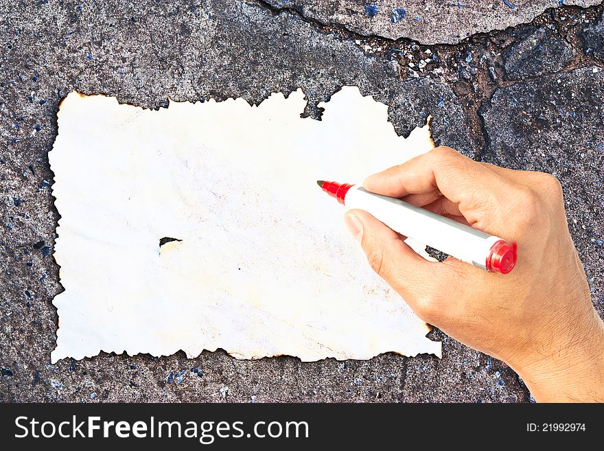 Writing hand at burn paper on concrete background