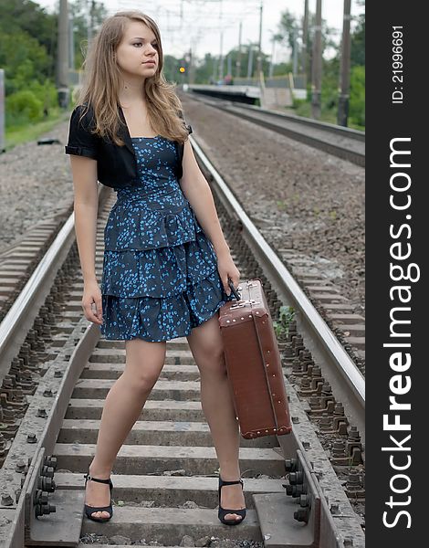 Girl with a suitcase standing on the rails