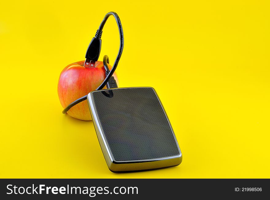 Hard disk and a cable that leads from a apple, photographed against a yellow background. Hard disk and a cable that leads from a apple, photographed against a yellow background