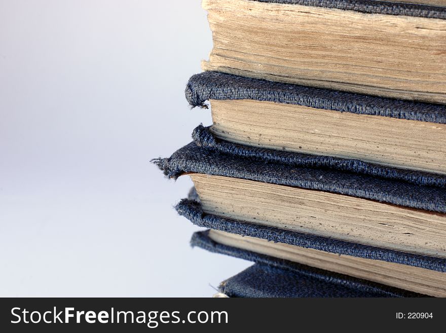 A pile of tatty, grungy old books with yellowing pages and worn blue covers. A pile of tatty, grungy old books with yellowing pages and worn blue covers.