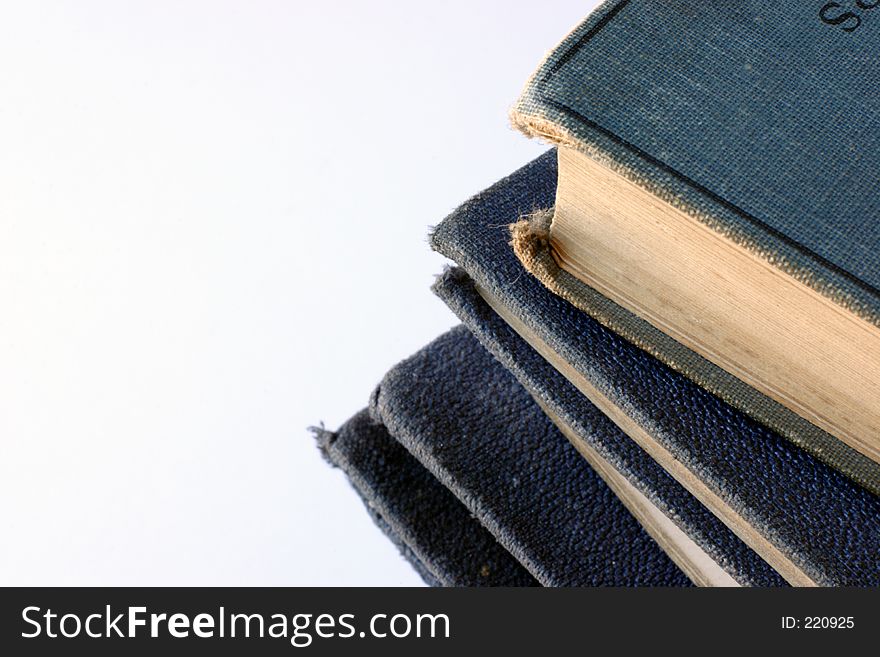 A pile of tatty, grungy old books with yellowing pages and worn blue covers. A pile of tatty, grungy old books with yellowing pages and worn blue covers.