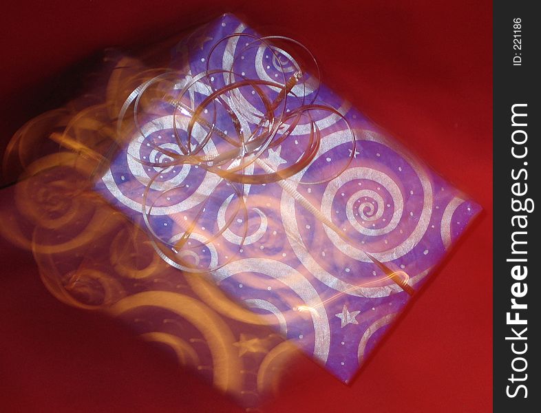 Blue and silver swirly gift on red background with copy blur. Blue and silver swirly gift on red background with copy blur