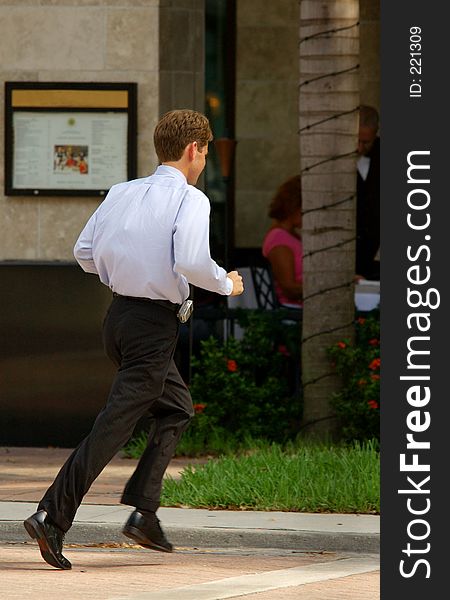 Businessman running across street with cell phone to cafe