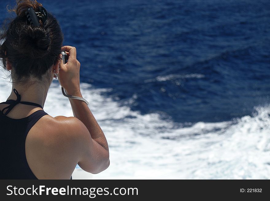 A girl takes a picture from a boat. A girl takes a picture from a boat