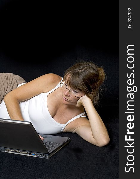 Pregnant woman lying down surfing the web on a laptop. Pregnant woman lying down surfing the web on a laptop