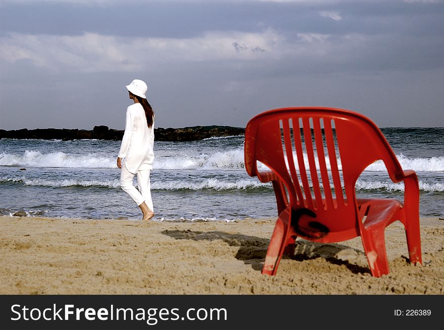 Lady in white on the seashore with red chair