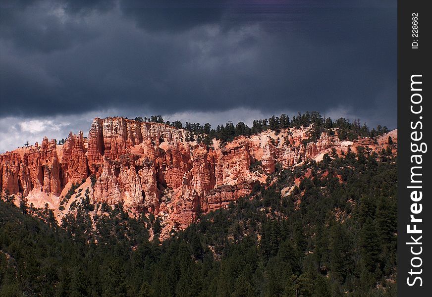 Dark storm clouds are over cliffs of red rock. Dark storm clouds are over cliffs of red rock.