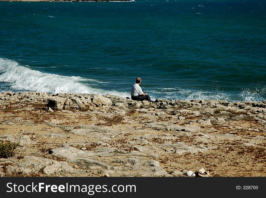 Man sitting on the rocks looking out the sea. Man sitting on the rocks looking out the sea
