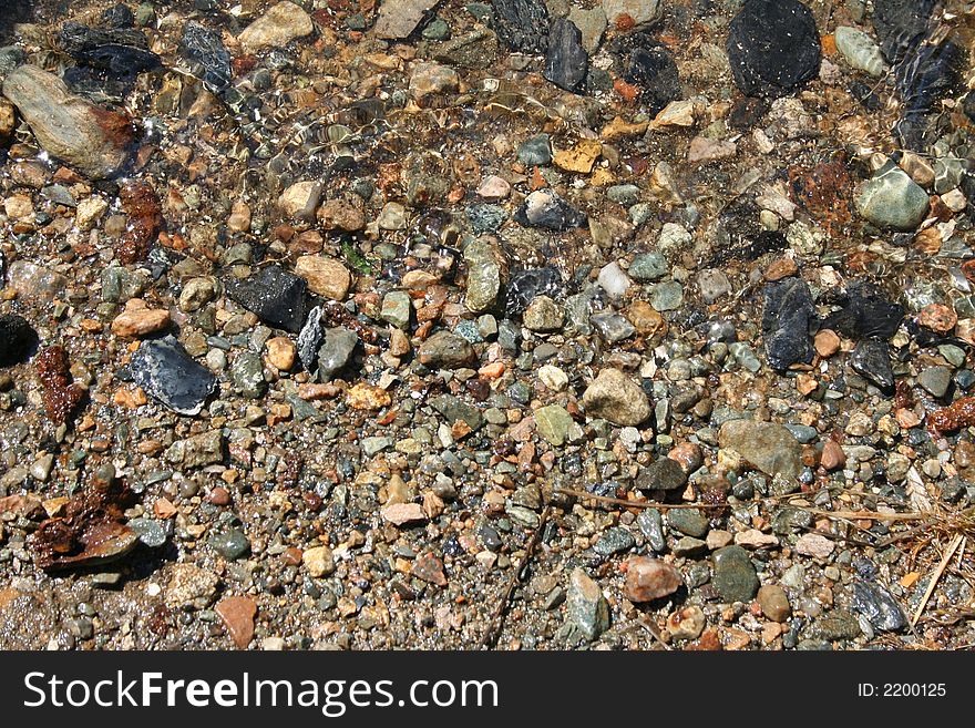 Overhead view of wet stone and rocks on shoreline of river. Overhead view of wet stone and rocks on shoreline of river.