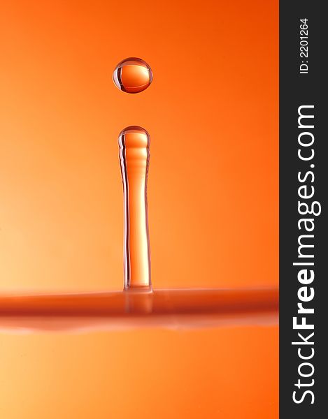 Water droplet over orange background, high speed photography.