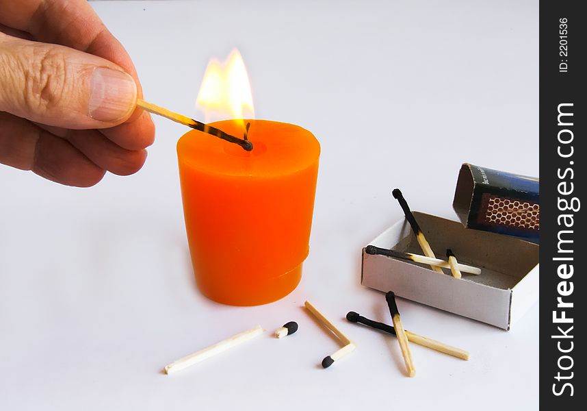 Burning candle, matchbox and hand holding a  ignition of match - on white background. Burning candle, matchbox and hand holding a  ignition of match - on white background