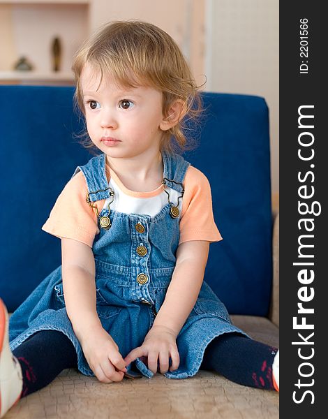 Little cute girl sitting on the sofa.