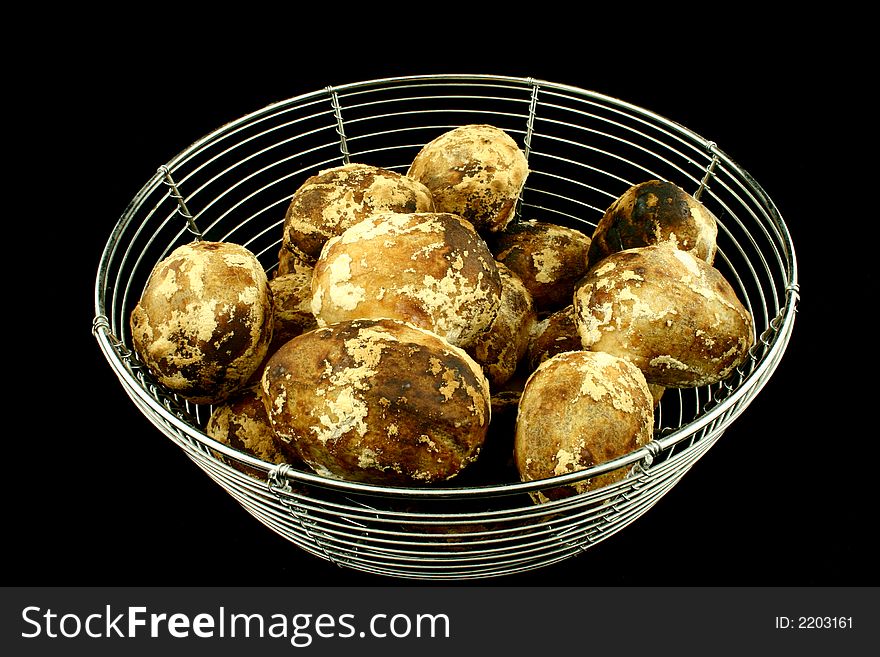 Wire bowl full of baked potatoes on a black background. Wire bowl full of baked potatoes on a black background