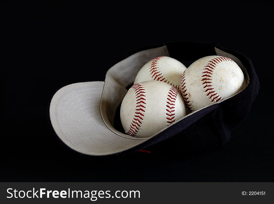 Blue baseball hat and three balls inside on a black background