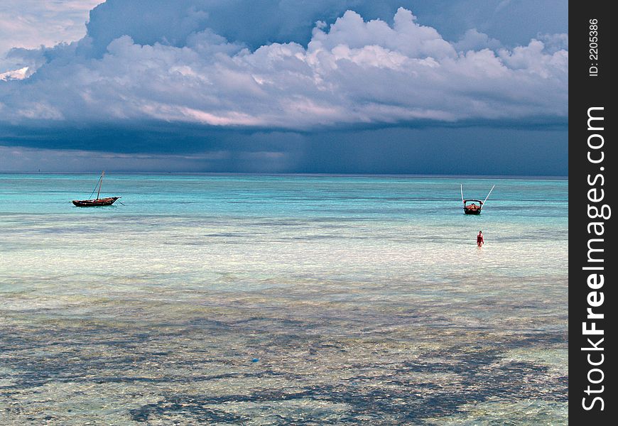 Lonely woman and sailboats near oceanfront. Indian Ocean. Island Zanzibar, Tanzania. Lonely woman and sailboats near oceanfront. Indian Ocean. Island Zanzibar, Tanzania.