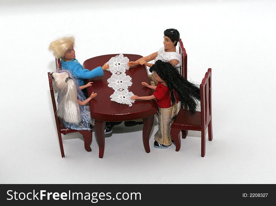 A macro shot of a toy family sitting at a dining table. isoalated on white. A macro shot of a toy family sitting at a dining table. isoalated on white