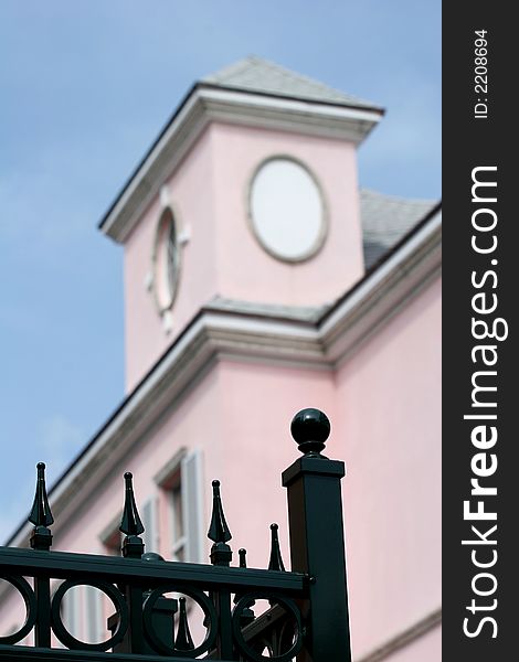 Black wrought iron fence with OOF pink building in background. Black wrought iron fence with OOF pink building in background