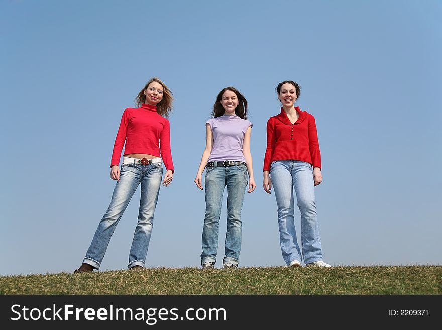 Girls stand on meadow against a blue sky