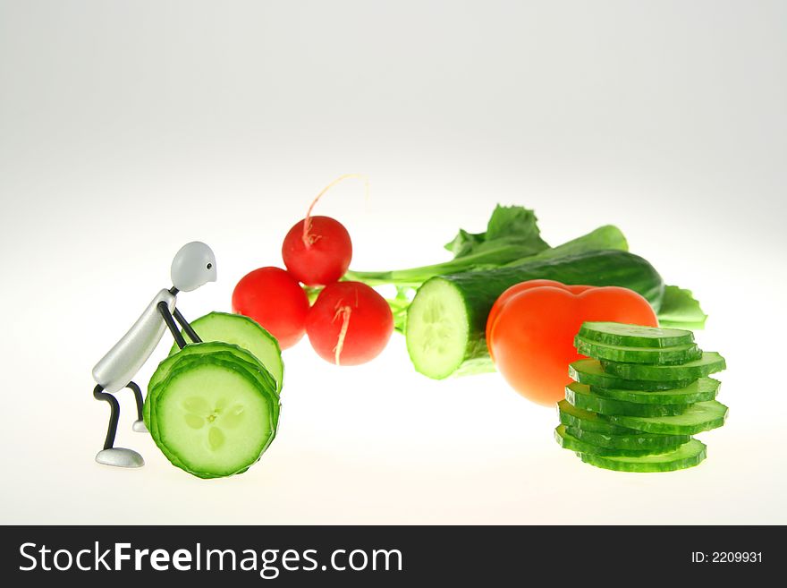 Weight-lifter and green cucumber and red radish and red tomato on white background. Weight-lifter and green cucumber and red radish and red tomato on white background