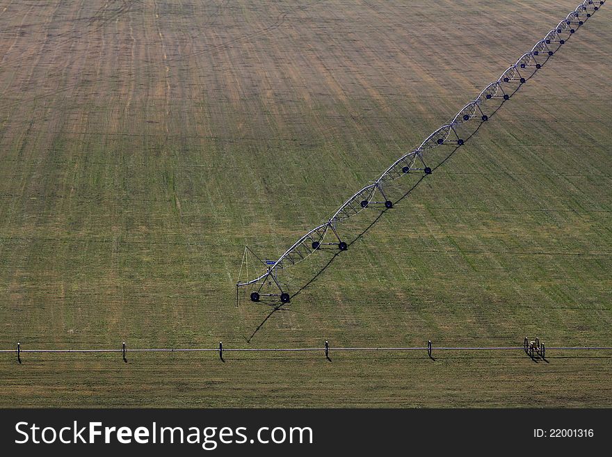 Aerial view of a pivot sprayer and sprinklers on a wide open farm field for farm irrigation. Aerial view of a pivot sprayer and sprinklers on a wide open farm field for farm irrigation.