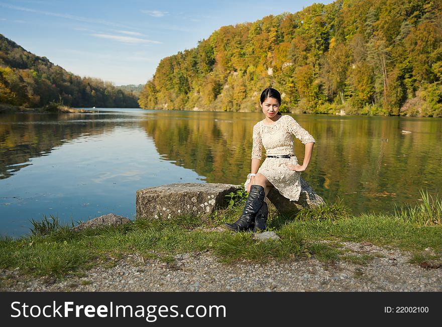 Beautiful asian sitting nearby a river in autumn. Beautiful asian sitting nearby a river in autumn