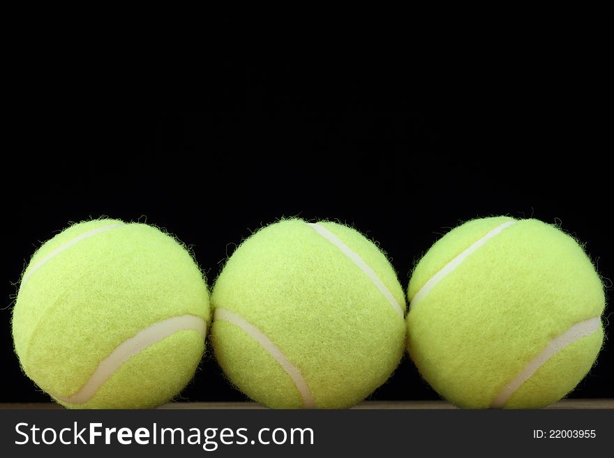 Three tennis balls on black background