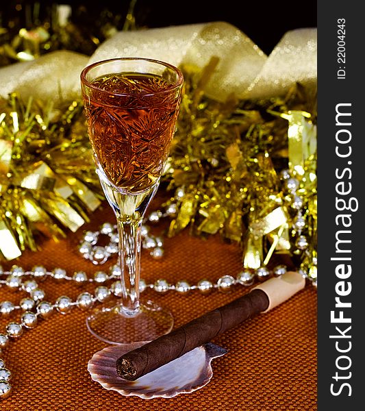 Crystal glass with brandy, cigars and Christmas decorations on a black background