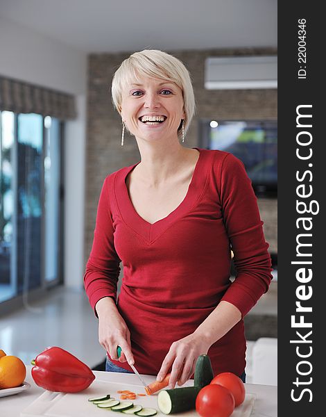 Happy young beautiful blonde woman prepare food in the kitchen at home. Happy young beautiful blonde woman prepare food in the kitchen at home