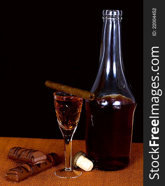 A bottle of brandy and cognac glass crystal, chocolate and cigar. A bottle of brandy and cognac glass crystal, chocolate and cigar
