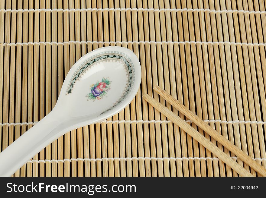 Soup spoon and chopsticks on tray bamboo background