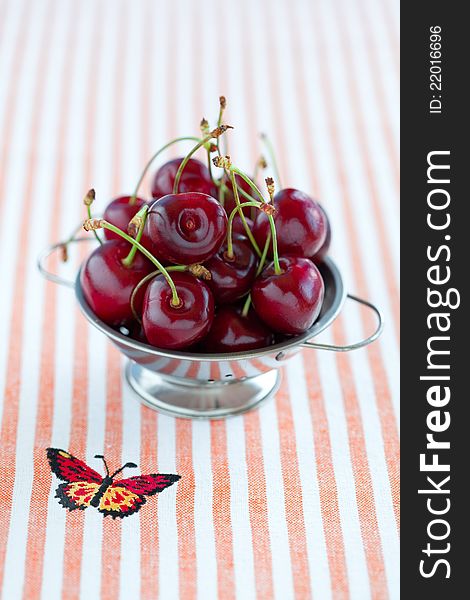 Fresh cherries in metal colander, selective focus